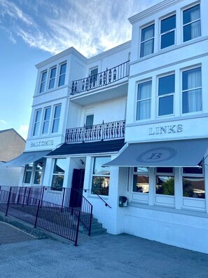A white building with multiple stories, featuring balconies and awnings with signage. - Balcomie Links Hotel (Anstruther)