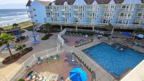 A hotel with a pool, outdoor seating, and a view of the ocean. - Seascape 2309 2 Bedroom Condo by RedAwning (Galveston)
