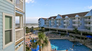 A hotel with a pool area, multiple balconies, and a view of the ocean.