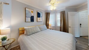Ein ordentlich eingerichtetes Schlafzimmer mit einem großen Bett, Nachttischlampen und zwei abstrakten Bildern an der Wand.
