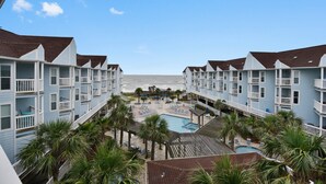 A hotel with multiple balconies, a pool area, and a view of the beach. - Seascape 2301 2 Bedroom Condo by RedAwning (Galveston)