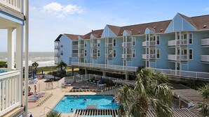 Een hotel met een zwembad, meerdere balkons en uitzicht op de oceaan.