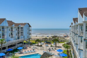 Een strandhotel met meerdere balkons, een zwembad en directe toegang tot het strand.