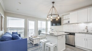 A modern kitchen with white cabinets, a stainless steel dishwasher, and a granite countertop. - Seascape 1304 Studio Bedroom Condo by RedAwning (Galveston)