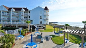 A beachfront hotel with multiple balconies, outdoor seating, and a pool area. - Seascape 1304 Studio Bedroom Condo by RedAwning (Galveston)