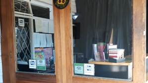 Une porte en bois avec une pancarte indiquant « Bienvenue » et un autocollant signalant la présence d’une auberge de jeunesse.