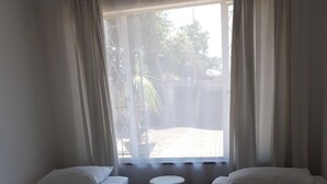 Une chambre avec deux lits, une petite table ronde et une fenêtre avec des rideaux.