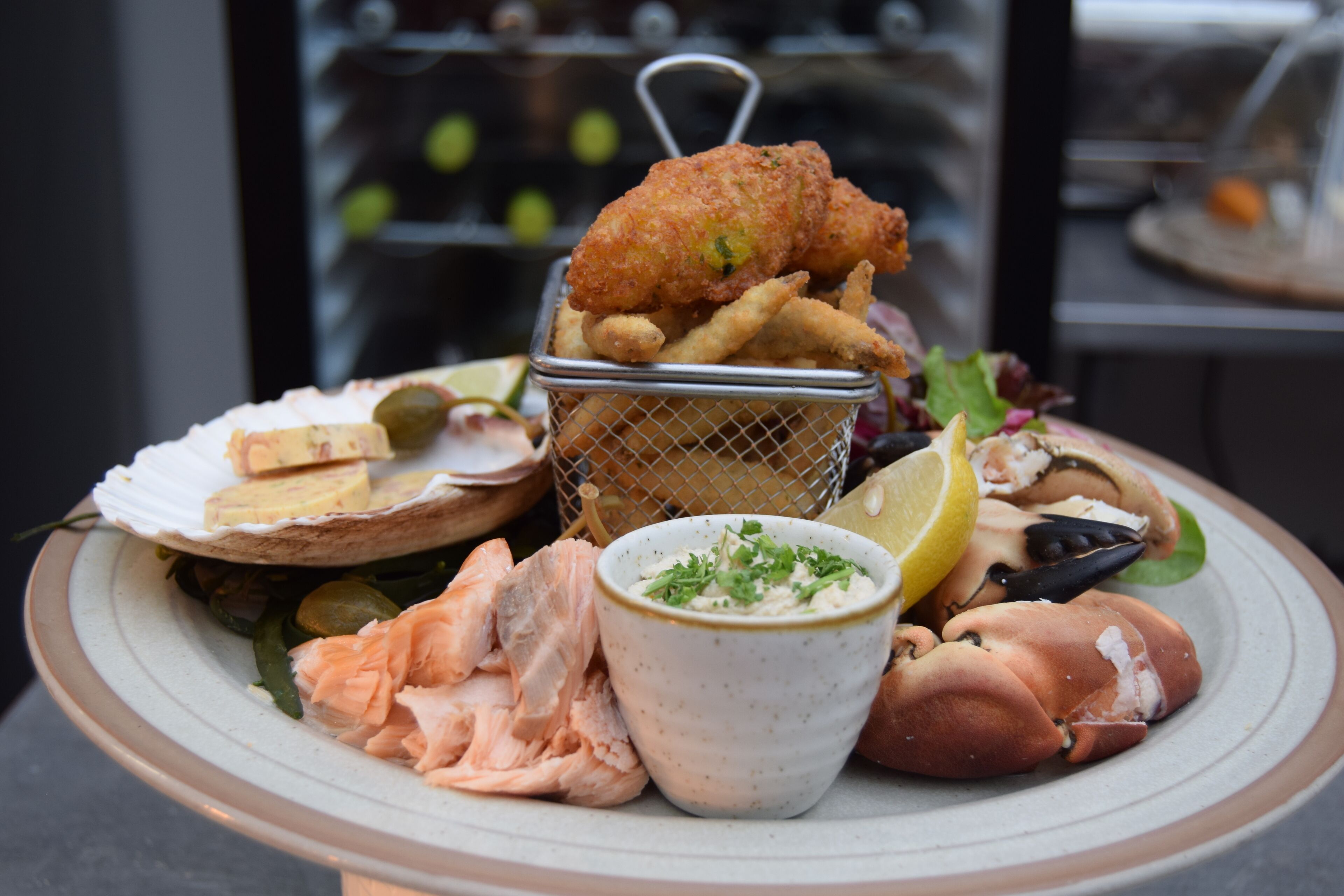 A seafood platter with various items including fish, shrimp, and a basket of fries.
