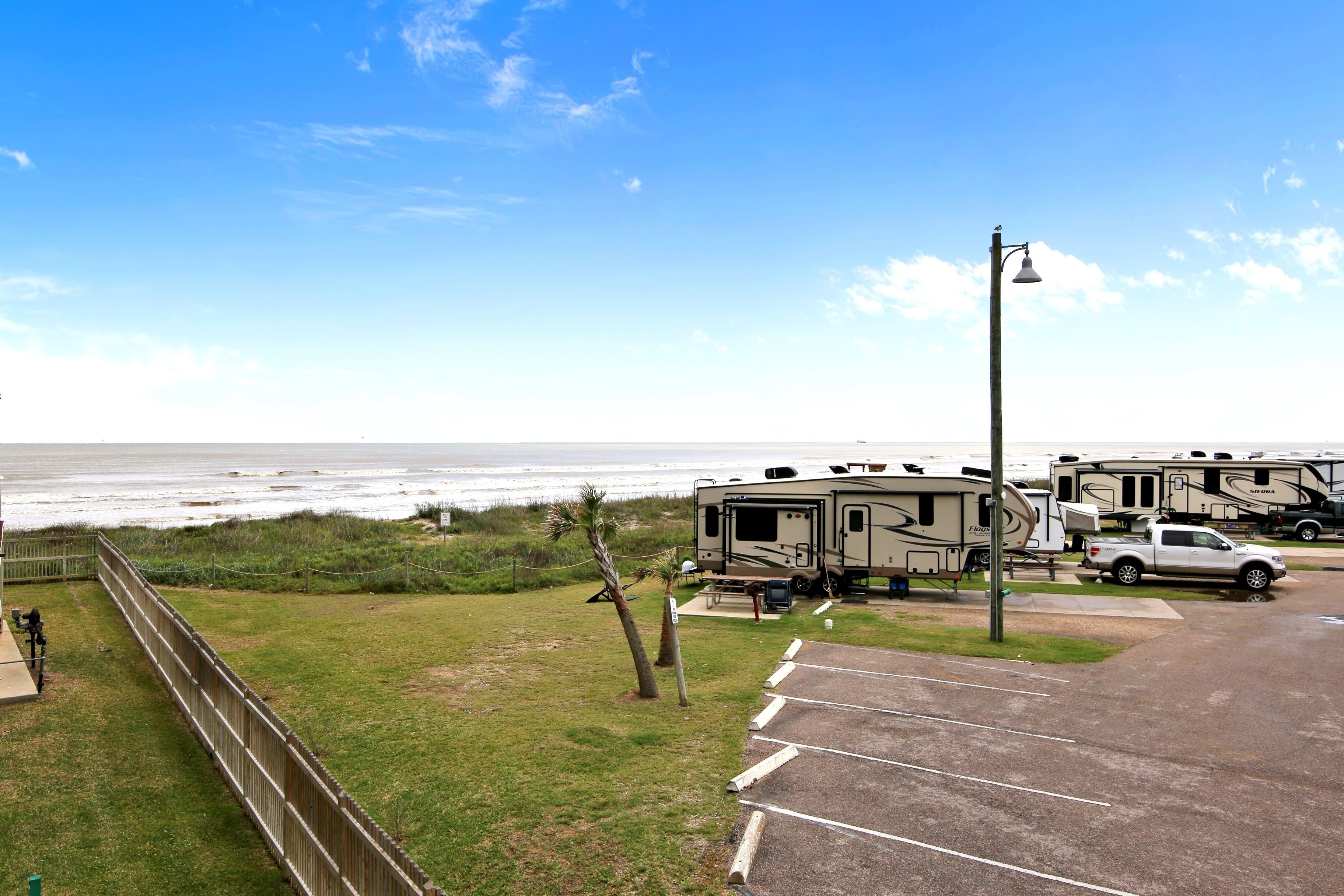 A campground with RVs, a parking lot, and a view of the ocean.