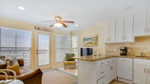 A spacious kitchen with white cabinets, a granite countertop, and a ceiling fan. - Seascape 1104 1 Bedroom Condo by RedAwning (Galveston)
