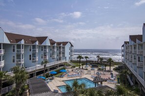 Un hôtel doté de nombreux balcons donnant sur une piscine et l’océan.