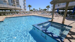 A pool area with clear blue water, lounge chairs, and a pergola.