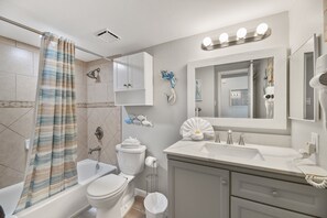 A bathroom with a bathtub, toilet, sink, and vanity.