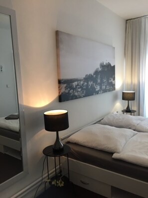 Une chambre d’hôtel comprenant un lit, des lampes de chevet, une grande œuvre d’art accrochée au mur et un miroir.