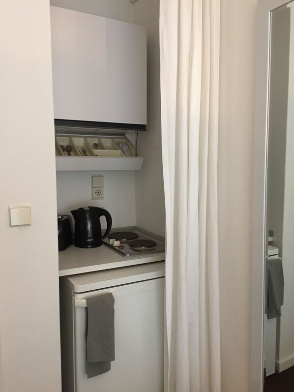 A compact kitchenette with a white refrigerator, a black coffee maker, and a microwave.
