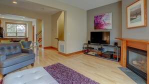 A modern living room with a grey sofa, a flat-screen TV, a fireplace, and a staircase leading to another room. - Spacious B2 Townhome with Fireplace and BBQ on the Deck by RedAwning (Hood River)