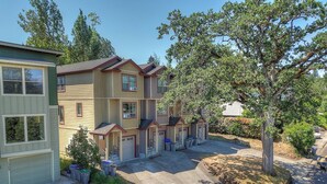 A multi-story residential building with a central courtyard, featuring a garage, a covered outdoor seating area, and a small garden. - Spacious B2 Townhome with Fireplace and BBQ on the Deck by RedAwning (Hood River)