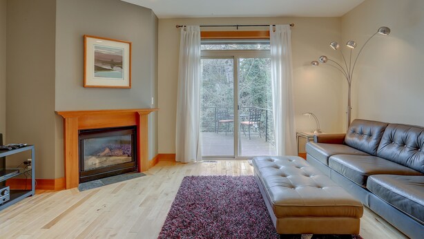 A living room with a fireplace, a sofa, a rug, and a large window with curtains. - Spacious B2 Townhome with Fireplace and BBQ on the Deck by RedAwning (Hood River)