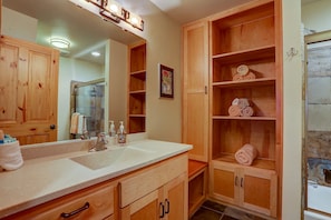 Un baño con armarios de madera, un lavabo y un espejo.