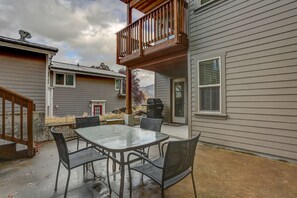 Un patio con mesa y sillas de vidrio, una terraza de madera y una parrilla.