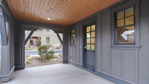 Een overdekte veranda met houten plafond en uitzicht op een woonstraat.