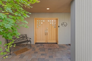 Enter through the beautifully designed entrance, featuring a double door with glass panels and a decorative emblem above.