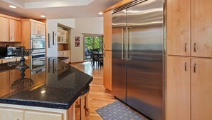 A modern kitchen with wooden cabinets, stainless steel appliances, and a black granite countertop.