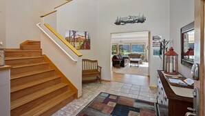 A staircase leading to a living area with a bench, a rug, and a door with a sign.