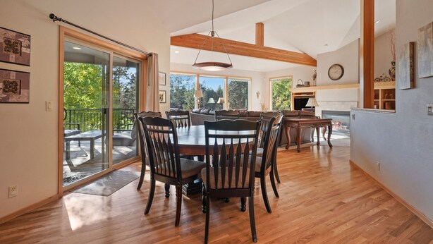 A spacious dining area with a wooden table and chairs, large windows, and a view of the outdoors.