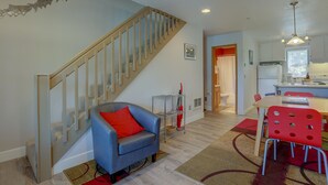 A modern living room with a staircase, a dining area with red chairs, and a kitchen in the background. - 13 Lodge Condo Minutes Away from Golfing, Biking, and Playground by RedAwning (Hood River)