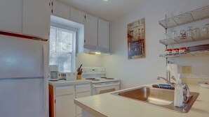 A kitchen with white cabinets, a stove, a sink, and a window with blinds. - 13 Lodge Condo Minutes Away from Golfing, Biking, and Playground by RedAwning (Hood River)