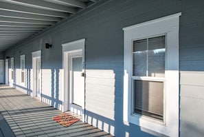A covered porch with a series of doors and windows, a patterned rug on the floor, and a number '21' on the wall. - Lodge 27 Roomy Condo with Gear Storage Onsite by RedAwning (Hood River)