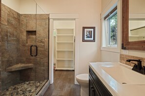 A modern bathroom with a glass-enclosed shower, a white toilet, and a large sink with a mirror. - Trails End 5 Bedroom Home by RedAwning (Bend)