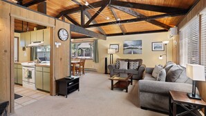 A cozy living room with a sofa, coffee table, and a dining area with chairs and a table. - 7 Grizzly Home New Private Hot Tub on the Deck and Bike for Adventure by RedAwning (Bend)