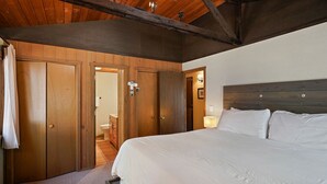 A bedroom with a large bed, wooden wardrobe, and a door leading to a bathroom. - 7 Grizzly Home New Private Hot Tub on the Deck and Bike for Adventure by RedAwning (Bend)