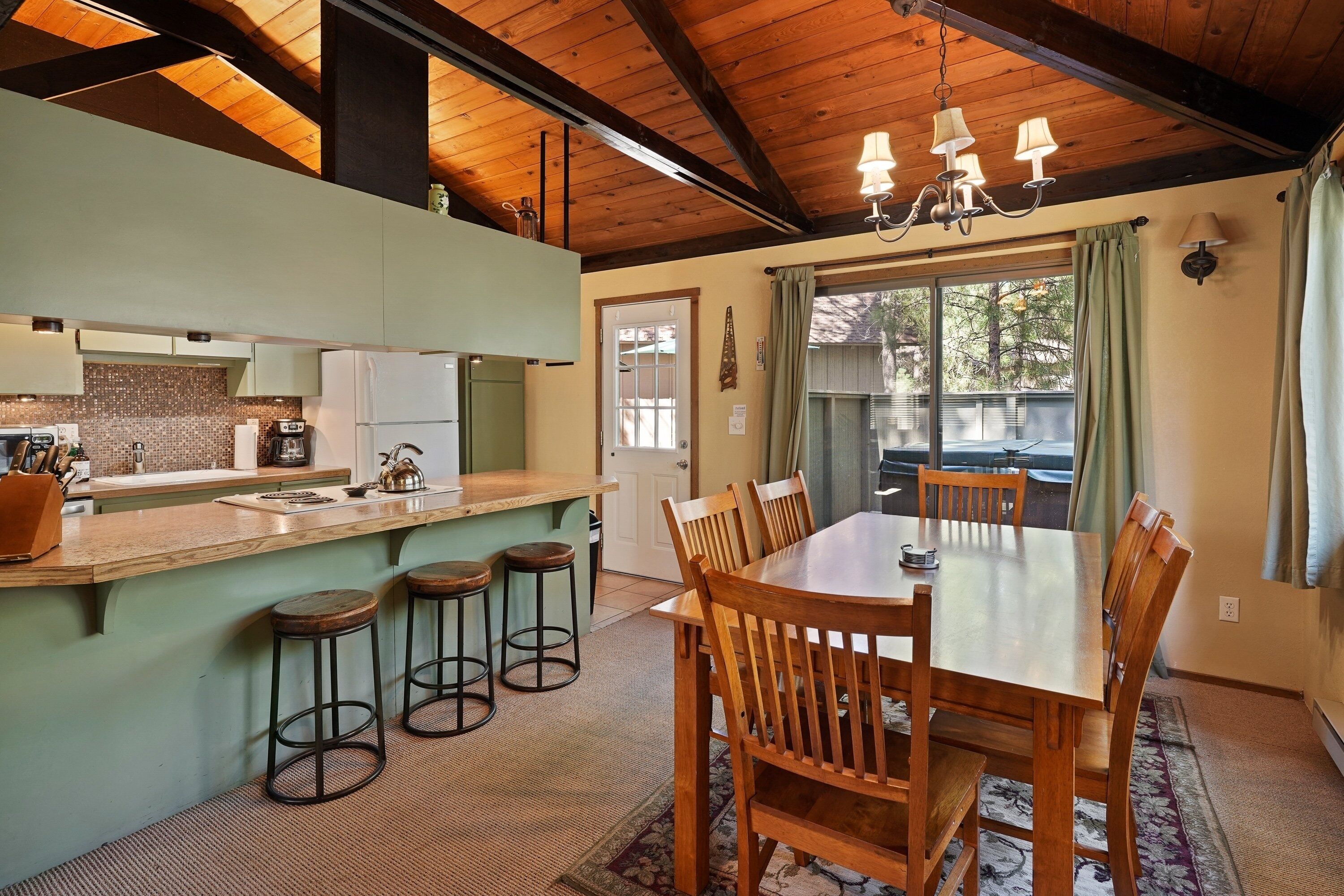 Una cocina amplia con una isla de madera, taburetes de bar y un comedor con mesa y sillas de madera.
