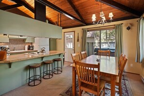 A spacious kitchen with a wooden island, bar stools, and a dining area with a wooden table and chairs.