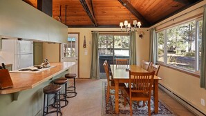 A kitchen with a wooden countertop, bar stools, and a dining area with a table and chairs. - 7 Grizzly Home New Private Hot Tub on the Deck and Bike for Adventure by RedAwning (Bend)