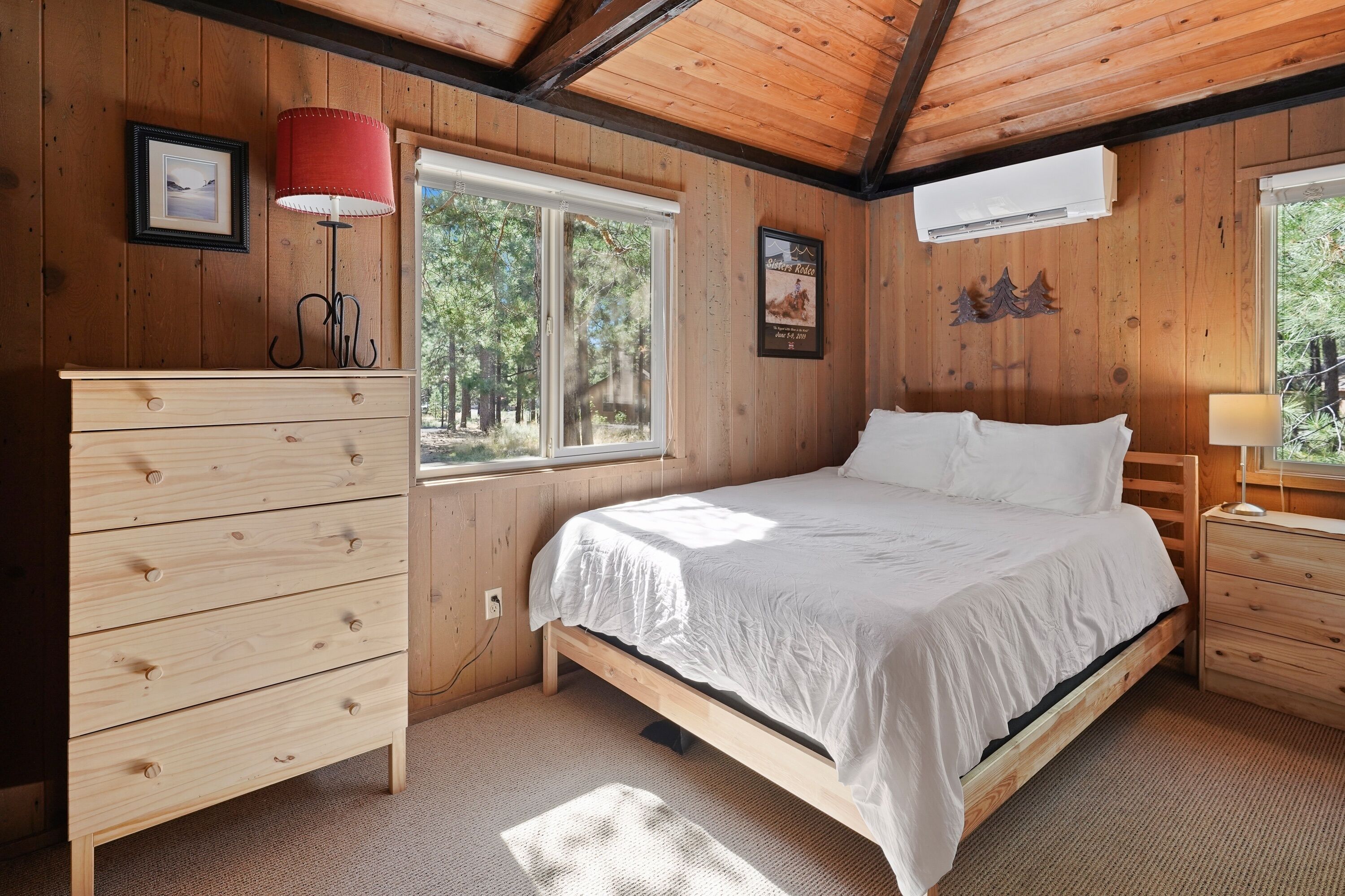 A wooden-paneled bedroom with a bed, dresser, and window.