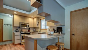 A modern kitchen with a central island, wooden stools, and built-in appliances. - Pet-Friendly 6 Otter Home features Bikes to Explore Sunriver Village by RedAwning (Bend)