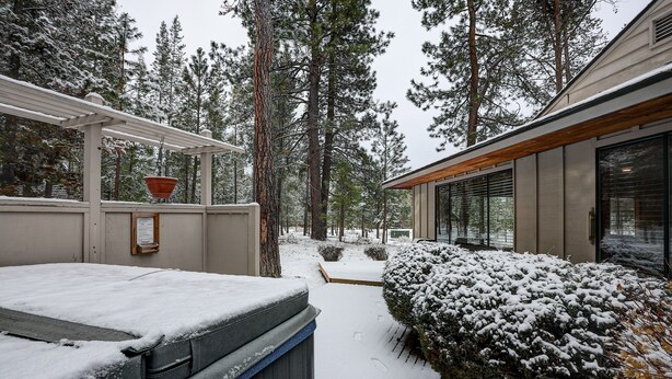 A snow-covered outdoor area with a wooden pergola, a hot tub, and a snow-covered bush. - Pet-Friendly 6 Otter Home features Bikes to Explore Sunriver Village by RedAwning (Bend)