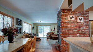 A dining area with a brick wall, wooden chairs, and a long table. - Pet-Friendly 6 Otter Home features Bikes to Explore Sunriver Village by RedAwning (Bend)