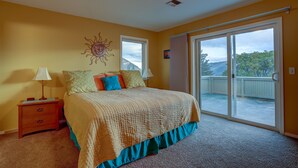 A bedroom with a bed, a nightstand, a window, and a sliding glass door leading to a balcony.