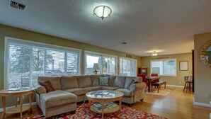 A living room with a sectional sofa, a glass coffee table, and a red patterned rug.