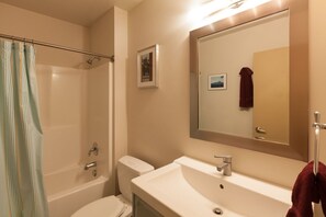 Ein Badezimmer mit Badewanne, Toilette, Waschbecken und einem großen Spiegel.