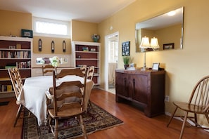Cozy dining area with a table, chairs, bookshelf, and potted plant.