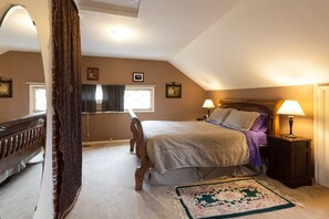 Un dormitorio con cama, mesitas de noche, un escritorio y una silla.