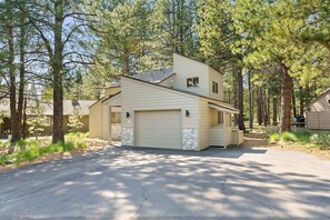 A single-story house with a garage, surrounded by tall pine trees. - 2 Landrise Pet-Friendly Home with Bikes to Use by RedAwning (Bend)