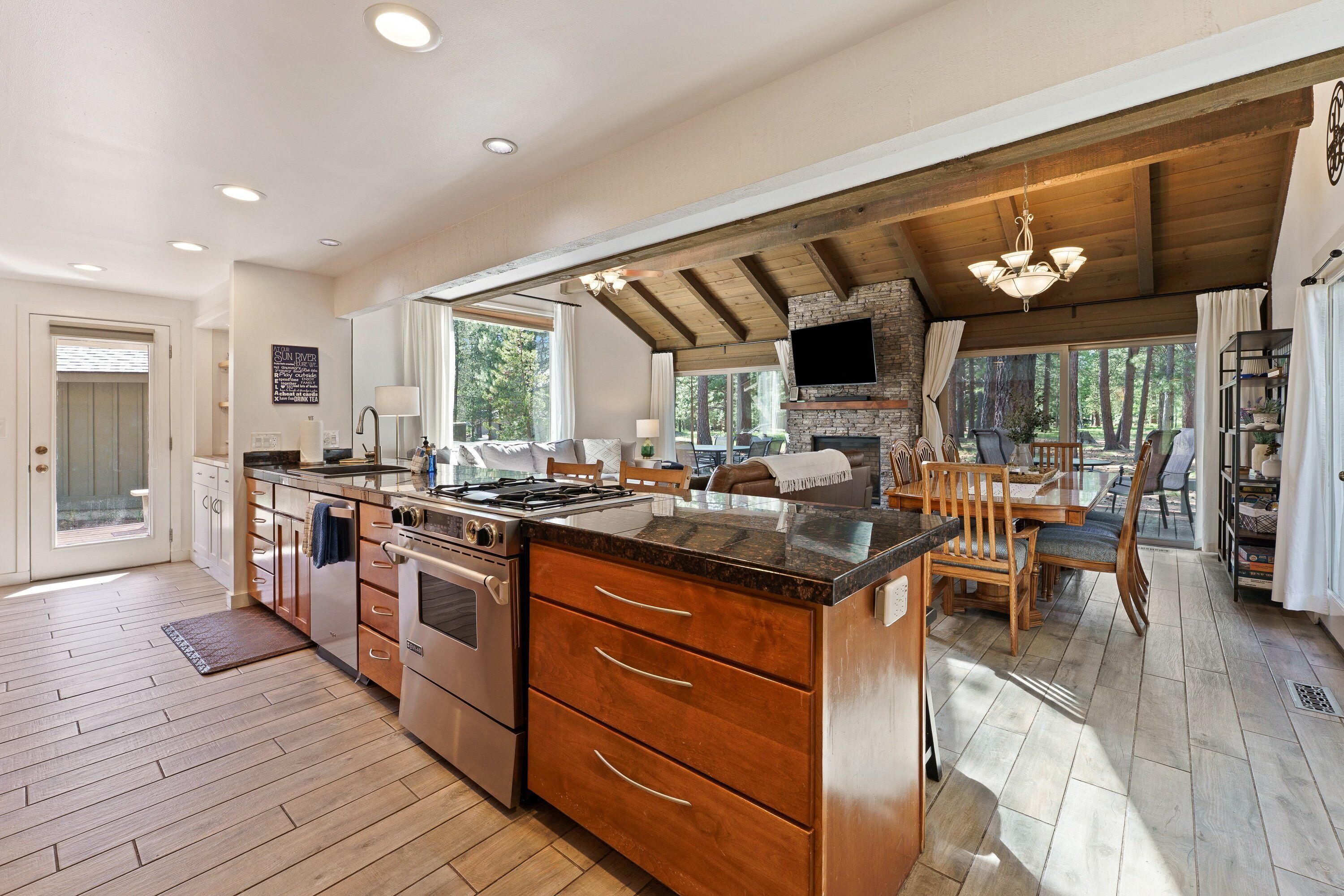 A spacious kitchen with wooden cabinets, a large island, and a stone fireplace.
