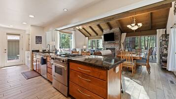 A spacious kitchen with wooden cabinets, a large island, and a stone fireplace.